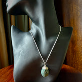 This picture shows a little jade acorn pendant with sterling silver chain. The cap is sterling silver and is embossed with some decorative markings which give the silver cap some detail and character. Hand made by Ana Krakosky.